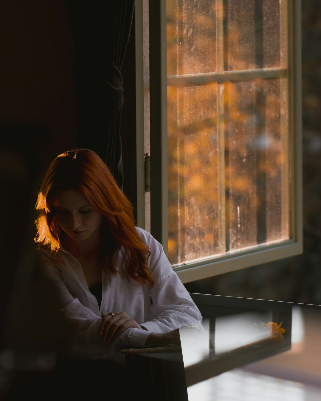 Woman writing thoughtfully in a journal by a window